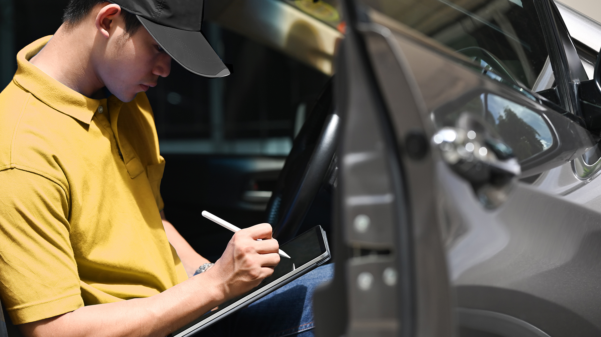 Home tenant une tablette et crayon intelligent devant un véhicule